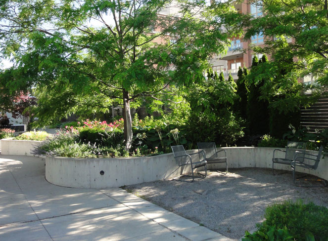 CNIB Headquarters - metal chairs in front of curvilinear concrete planter wall with trees and shrubs